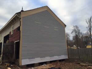 House with newly repaired side with grey siding