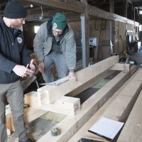 Colonial Restorations team measuring timber beam for historic barn structural repair