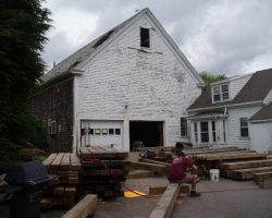 A man is standing in front of a white house.