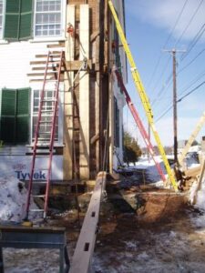 OLYMPUS DIGITAL CAMERA corner of white home being repaired with lumber