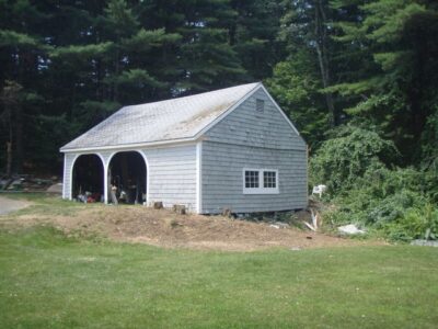 OLYMPUS DIGITAL CAMERA A white shed in a wooded area.