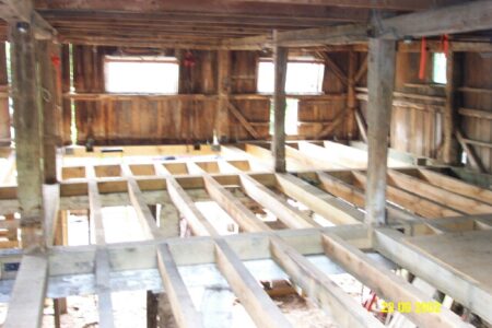 The inside of a barn with wood beams and windows.