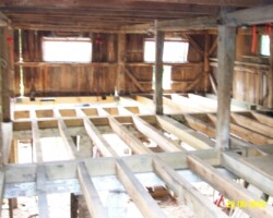 The inside of a barn with wood beams and windows.