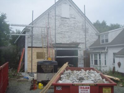 A white house under construction with a truck in front of it.