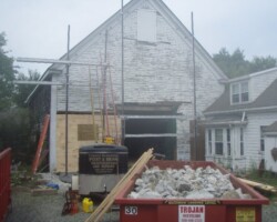 A white house under construction with a truck in front of it.