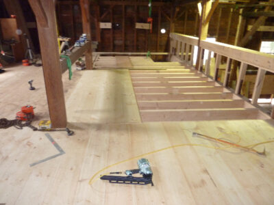 A wooden floor is being refinished in a barn.