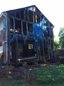 A house with blue netting hanging from the roof.