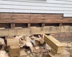 A house foundation being repaired with wood and bricks.