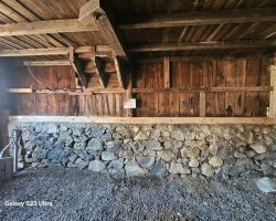 The inside of a barn with stone walls and a stone floor.