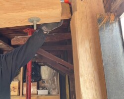 A man is working on a wooden beam in a garage.