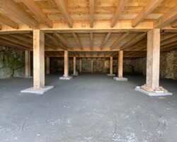An empty room with wooden beams and concrete floors.