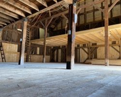 The inside of a barn with wooden floors and beams.